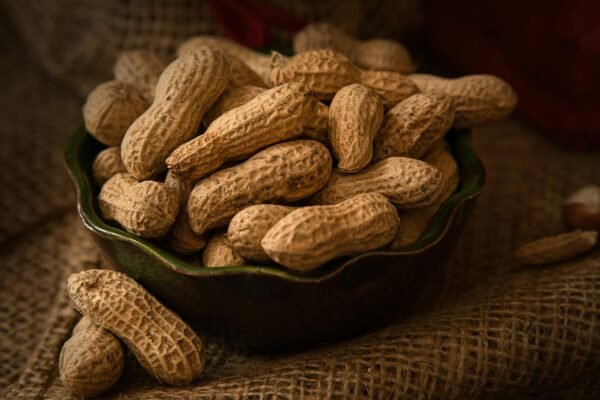 A rustic bowl filled with whole peanuts resting on a burlap cloth, evoking a natural and earthy feel.